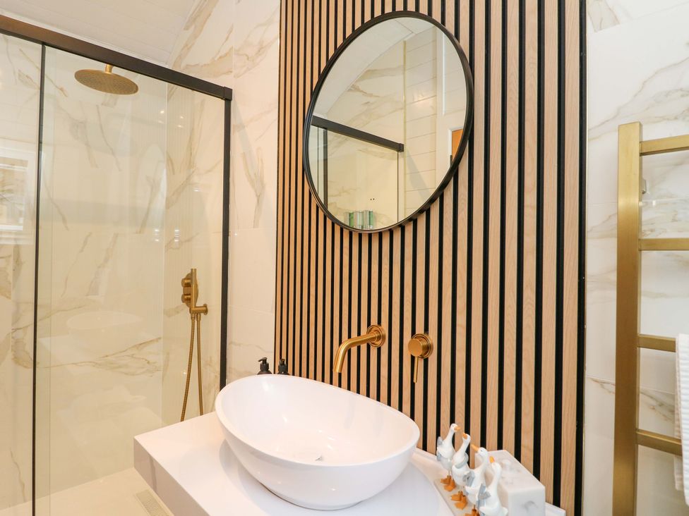 A bathroom with a shower, sink, and mirror at Crofters Suite in 