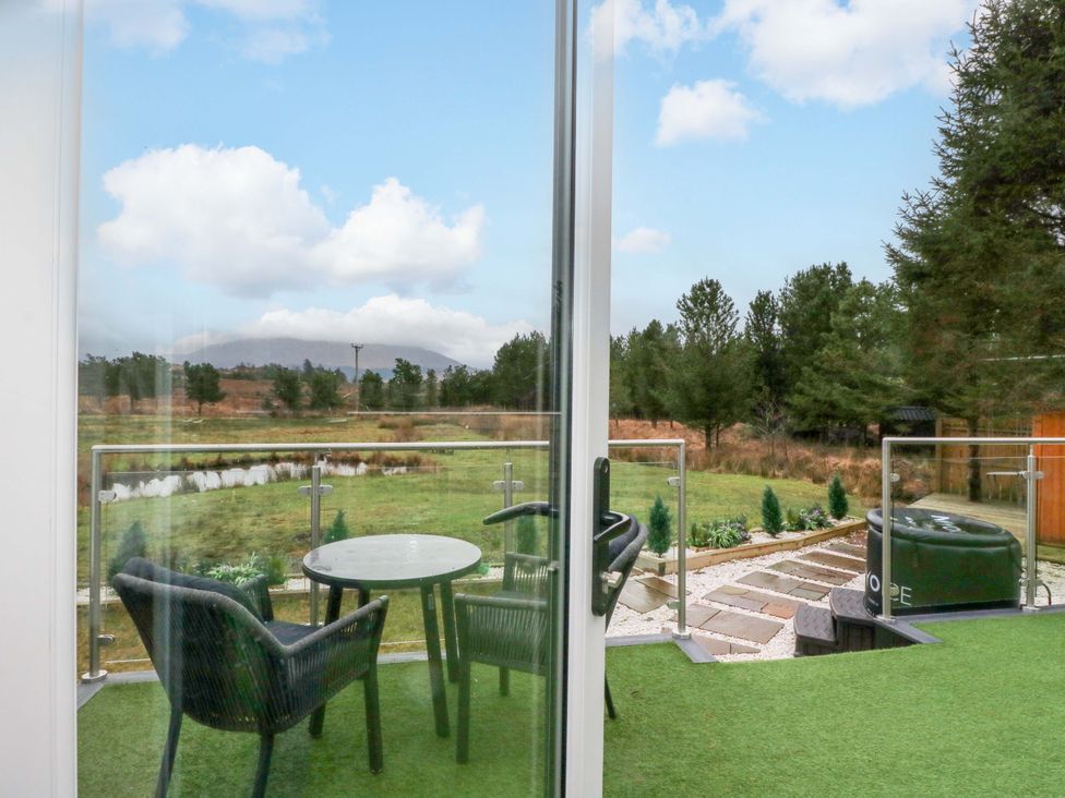 A balcony with a table and chairs overlooking a garden at Crofters Suite