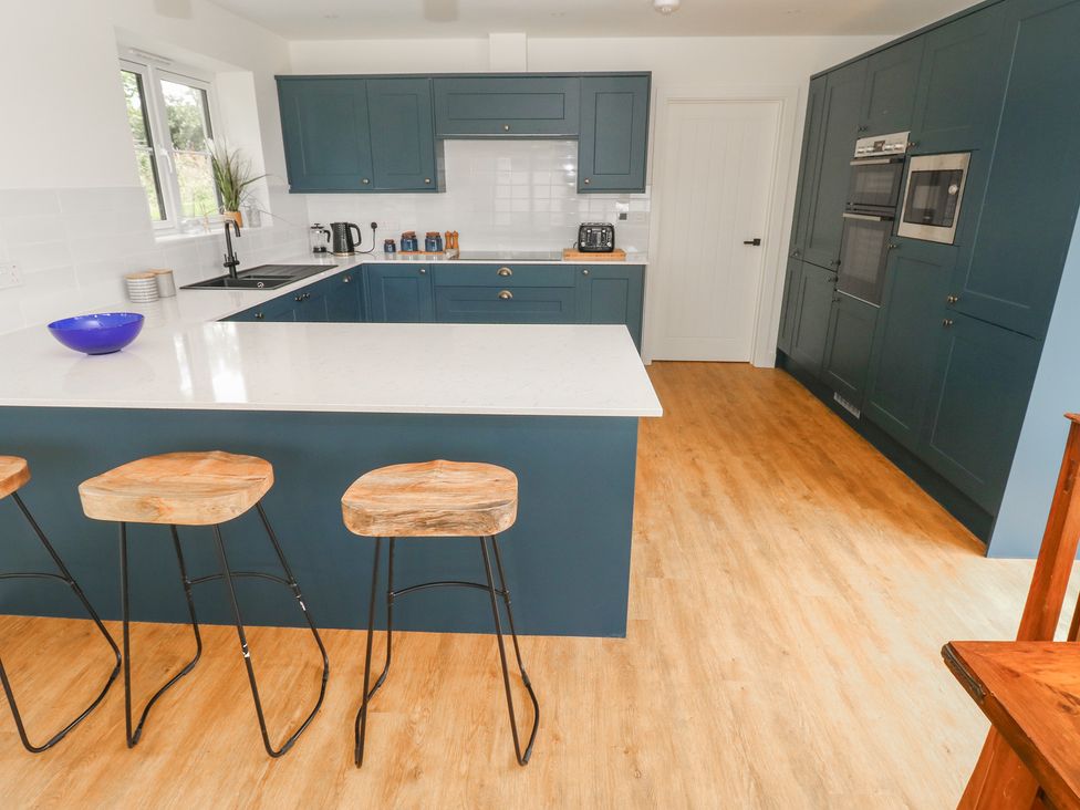 A kitchen with a kitchen island and stools at Ty Landsker in Milford Haven