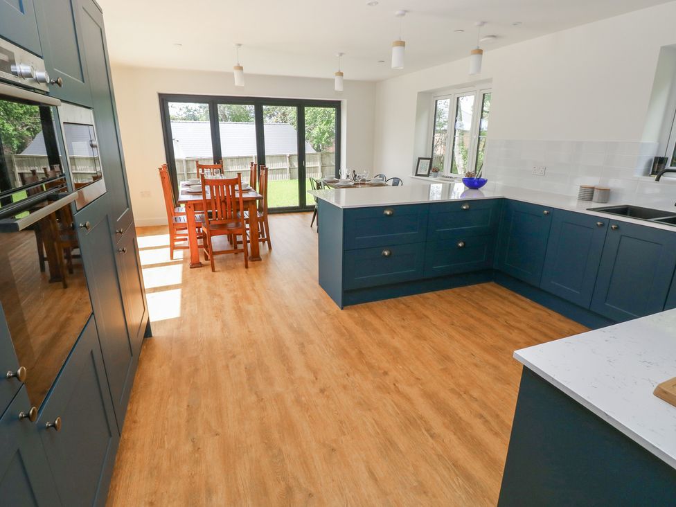 A kitchen with a dining area and large windows at Ty Landsker in Milford Haven