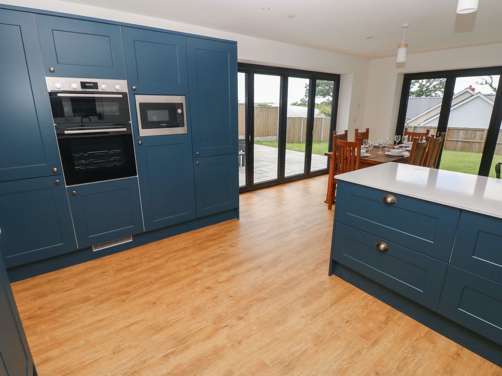 A kitchen with dark blue cabinets and a dining table at Ty Landsker in Milford Haven