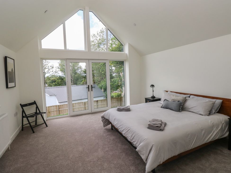 A bedroom with a bed and chair at Ty Landsker in Milford Haven