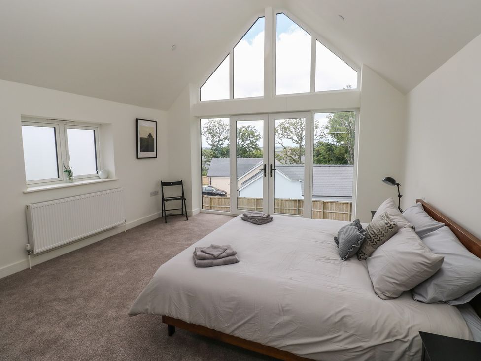 A bedroom with a bed and windows at Ty Landsker in Milford Haven