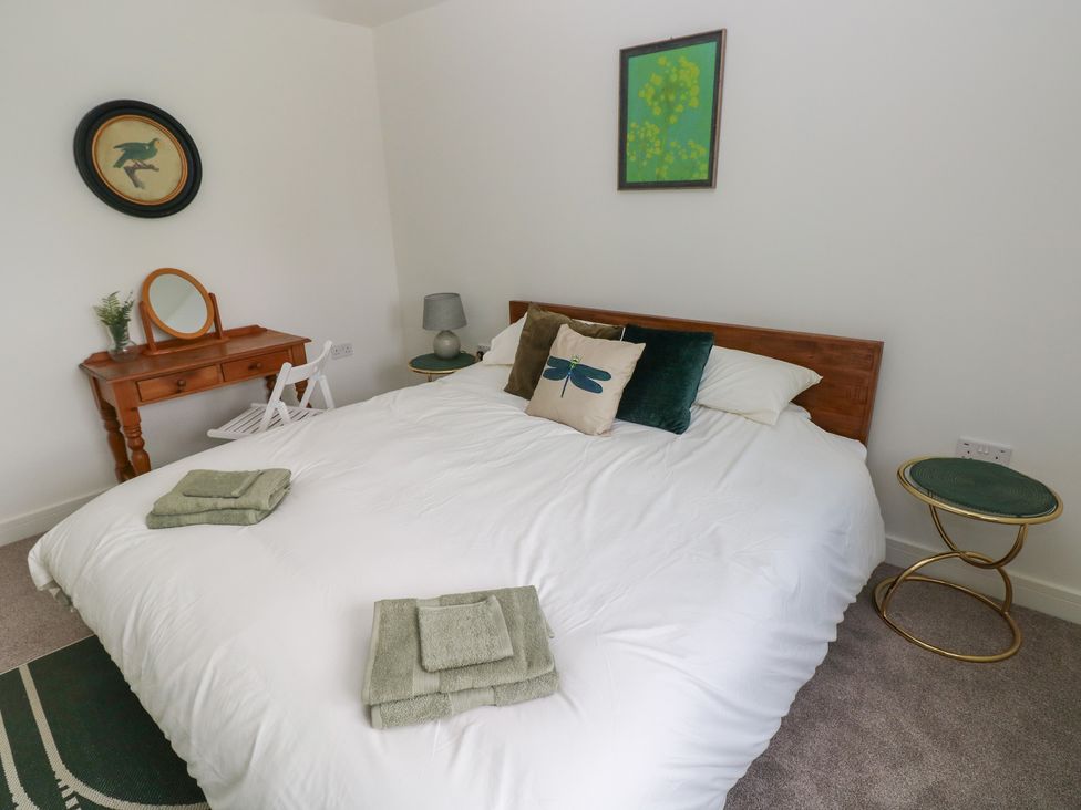 A bedroom with a bed and dresser at Ty Landsker in Milford Haven