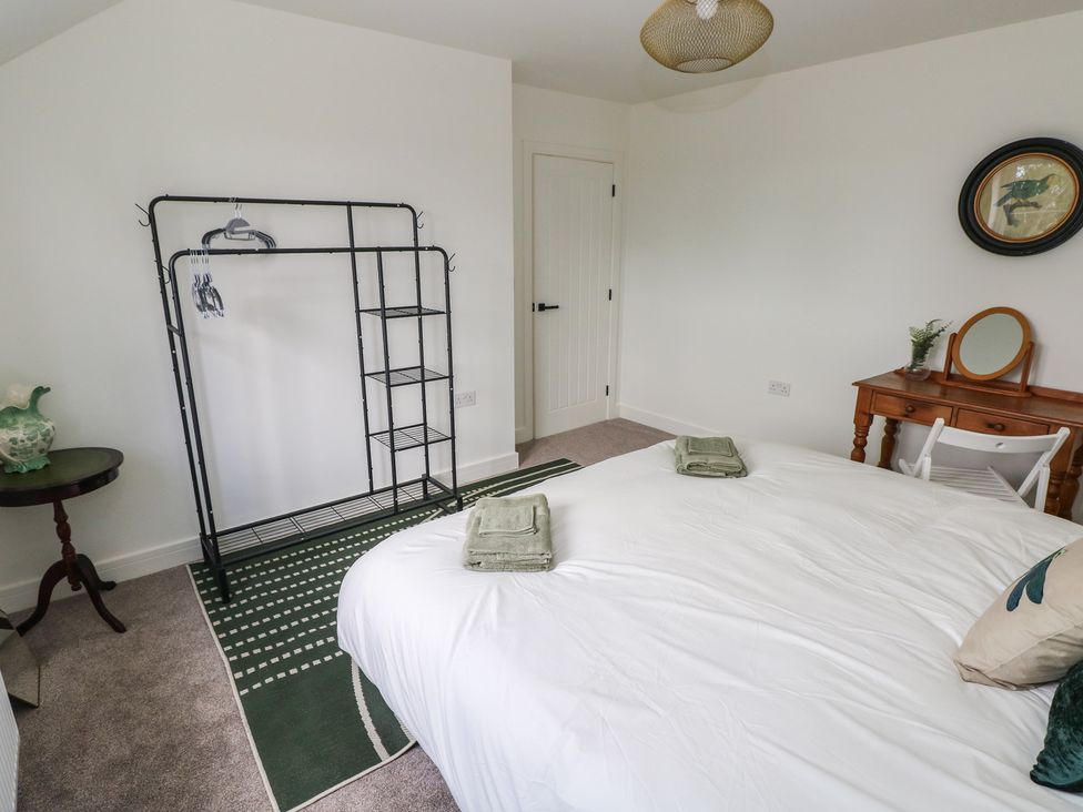 A bedroom with a bed and hanger rack at Ty Landsker in Milford Haven