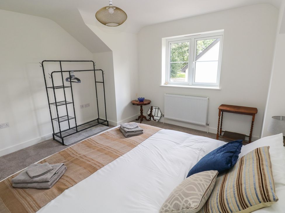 A bedroom with a bed, clothes rack and window at Ty Landsker in Milford Haven