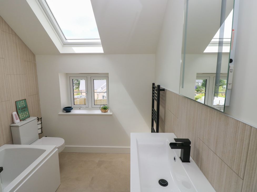 A bathroom with a bathtub, sink, and toilet at Ty Landsker in Milford Haven