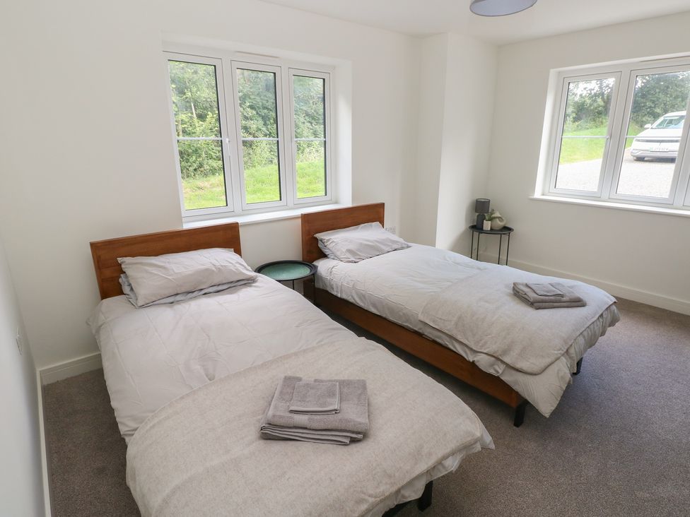 A bedroom with two beds and a side table at Ty Landsker in Milford Haven