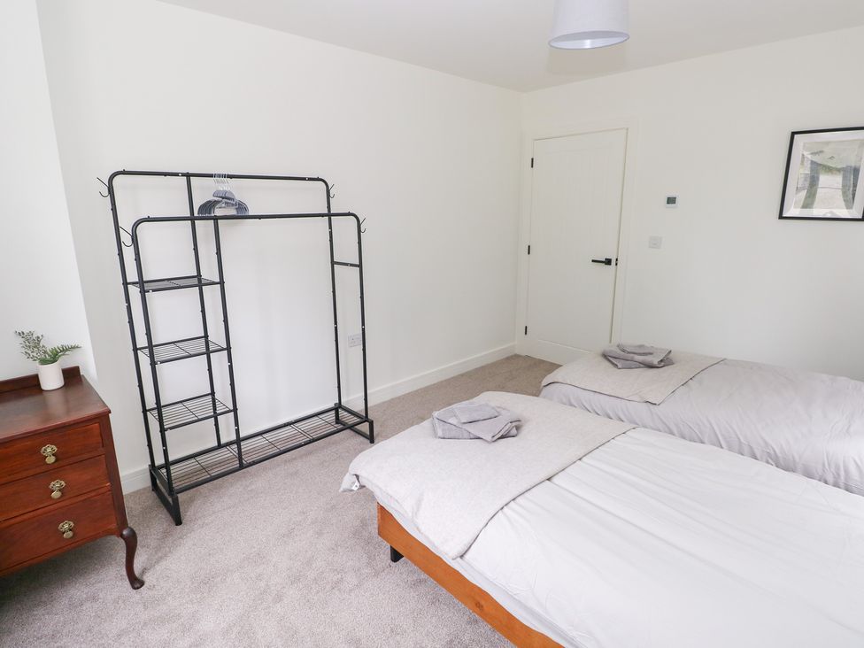 A bedroom with two beds and a clothing rack at Ty Landsker Houghton near Neyland