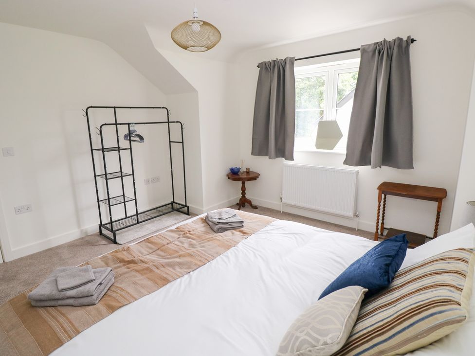 A bedroom with a bed and a clothes rack at Ty Landsker in Houghton near Neyland