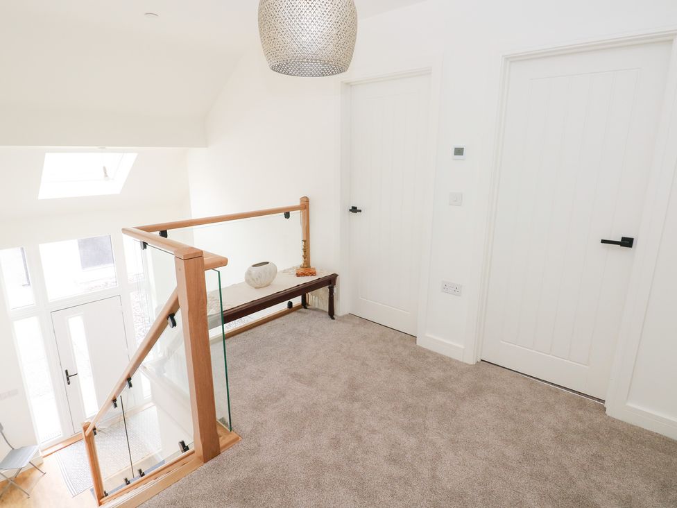 A hallway with a stair railing and white doors at Ty Landsker in Houghton near Neyland