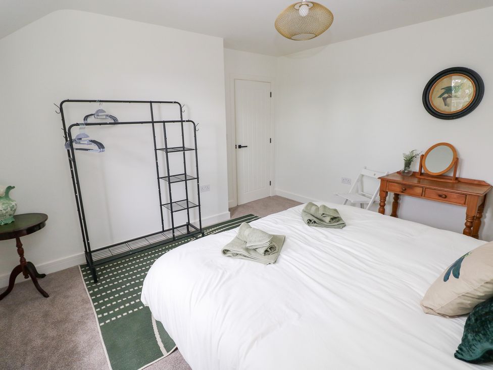 A bedroom with a bed and hanger rack at Ty Landsker in Houghton near Neyland