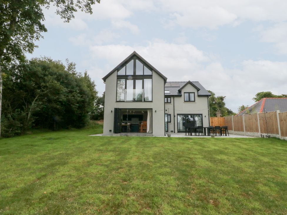 A house with windows and a patio in a yard at Ty Landsker in Houghton near Neyland