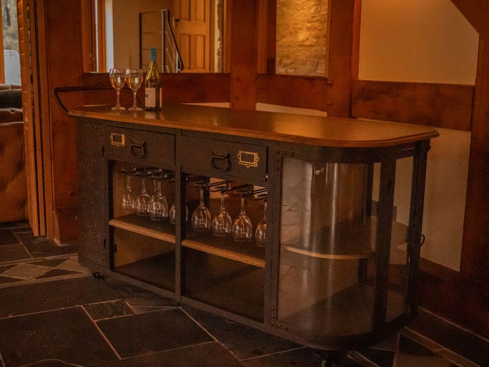 A bar cart with wine and glasses in a living room at Stud Farm House Bleddfa near Knighton