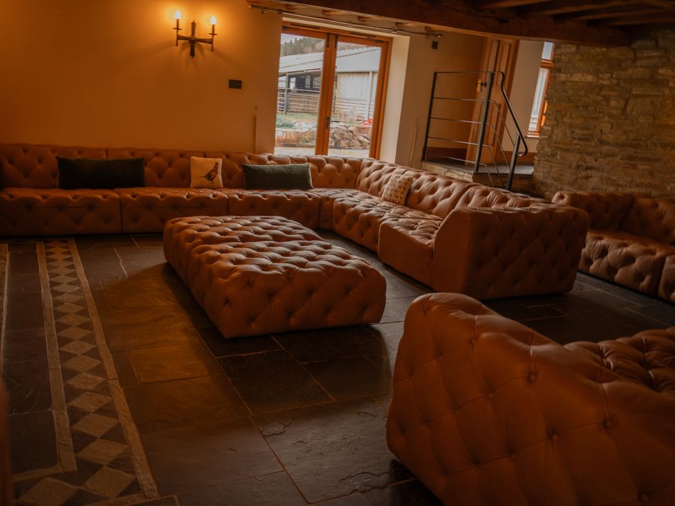 A living room with a large sofa and ottoman at Stud Farm House Bleddfa near Knighton