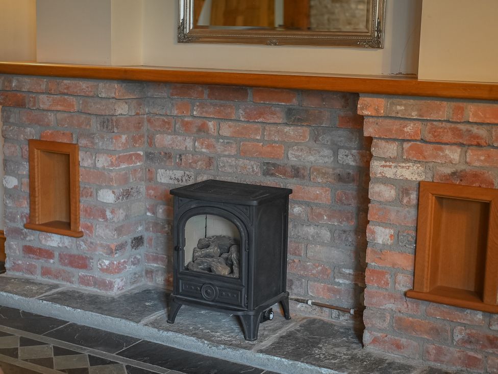 A fireplace with a wood stove and brick wall at Stud Farm House Bleddfa near Knighton