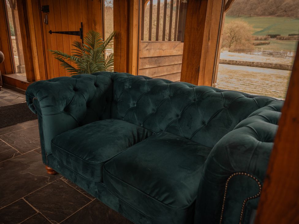 A couch with a plant and door in a sitting room at Stud Farm House in Bleddfa near Knighton