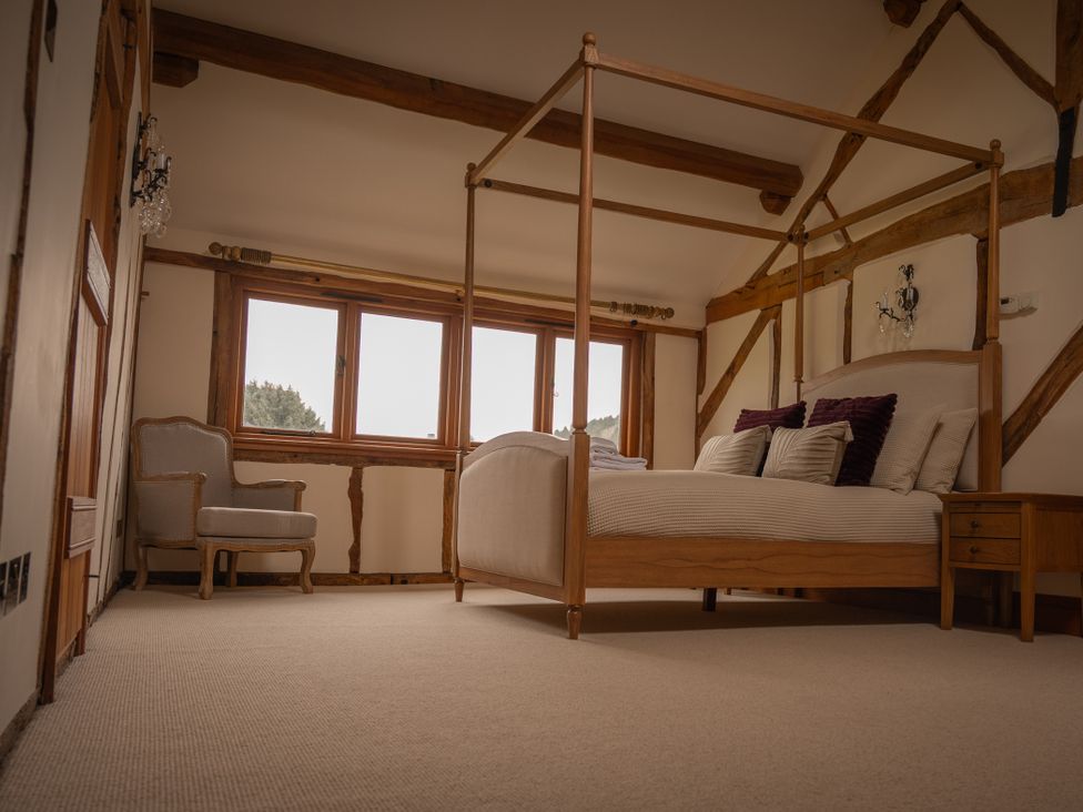 A bedroom with a four-poster bed and armchair at Stud Farm House Bleddfa near Knighton