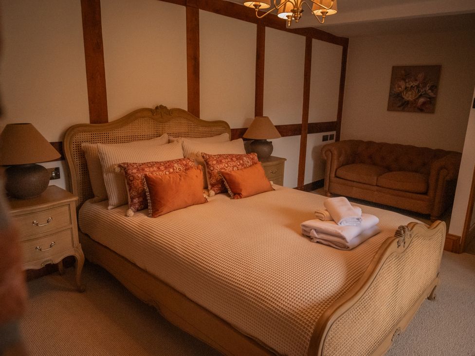 A bedroom with a bed, nightstand, lamp, and sofa at Stud Farm House Bleddfa near Knighton