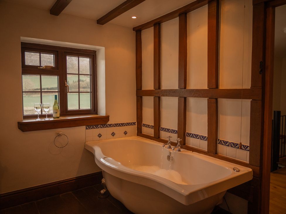 A bathroom with a bathtub and window at Stud Farm House in Bleddfa near Knighton