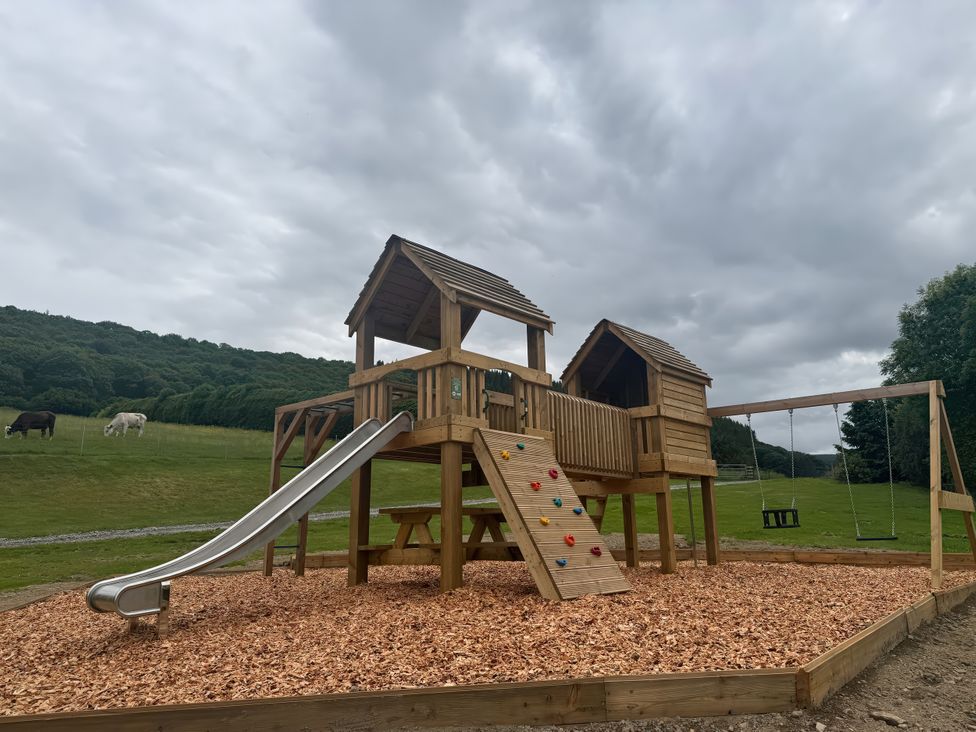 A playground with a slide climbing wall and swing at Stud Farm House Bleddfa near Knighton