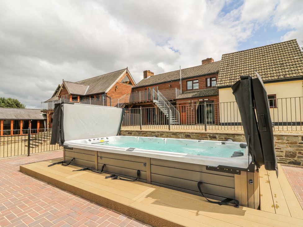 A hot tub on a deck with buildings in the background at Stud Farm House Bleddfa near Knighton