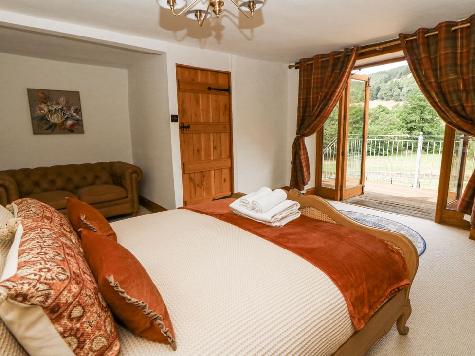 A bedroom with a bed, sofa and door at Stud Farm House Bleddfa near Knighton