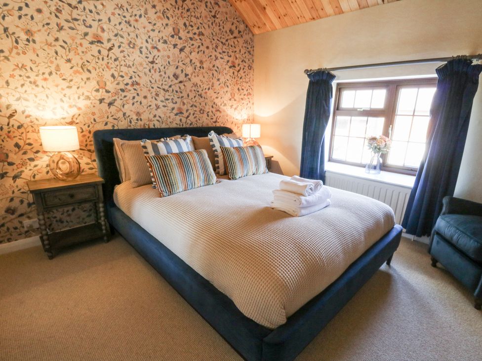 A bedroom with a bed, nightstand, and window at Stud Farm House Bleddfa near Knighton