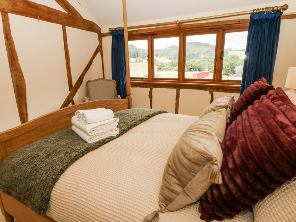 A bedroom with a bed and windows at Stud Farm House in Bleddfa near Knighton