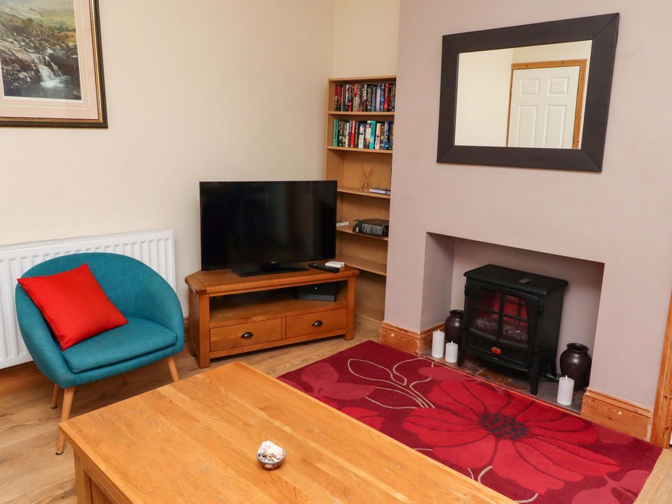A living room with a television and a bookshelf at Godetia Cottage in Seahouses
