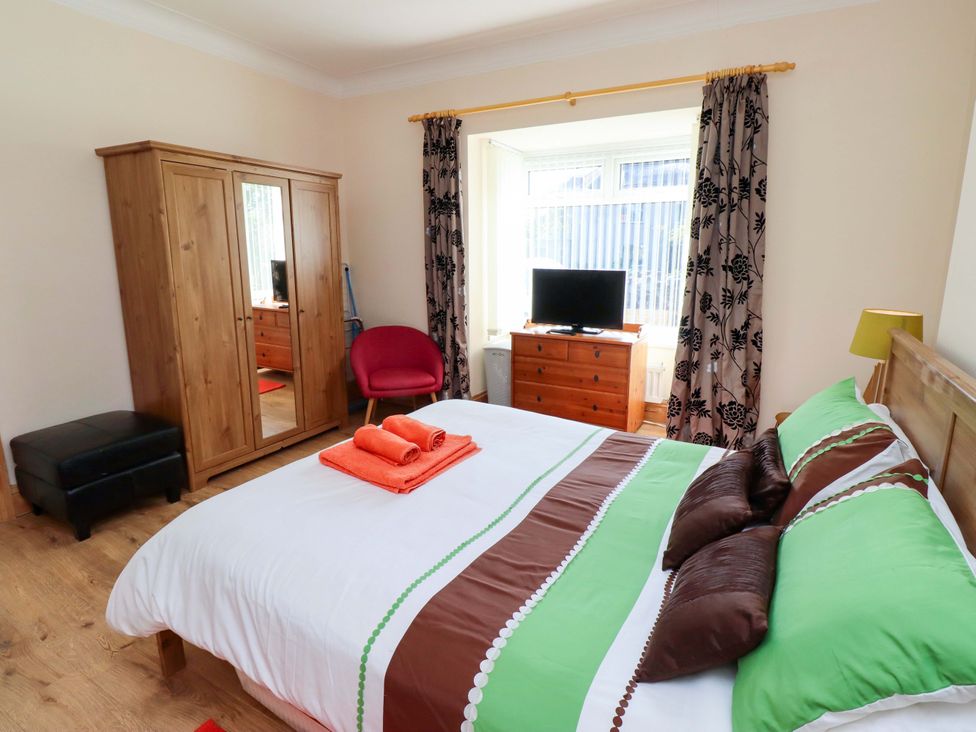 A bedroom with a double bed and wardrobe at Godetia Cottage Seahouses