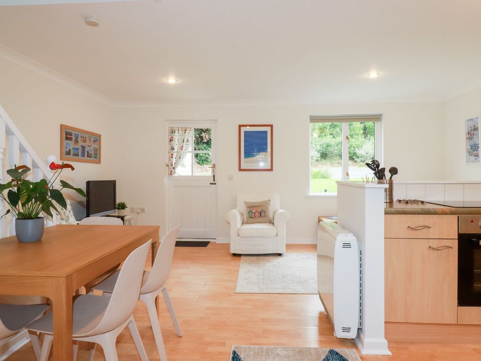 A living room with a dining table and chairs at Acorns, Falmouth