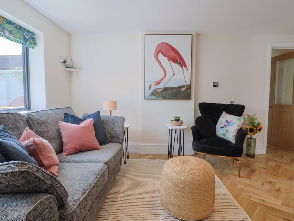 A living room with a flamingo painting and a sofa at 1 Mill Green Court, Lyme Regis