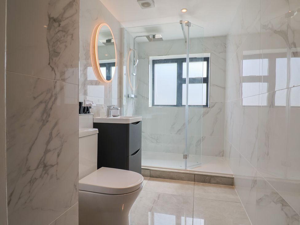 A bathroom with a shower, toilet, sink, and mirror at 1 Mill Green Court Lyme Regis