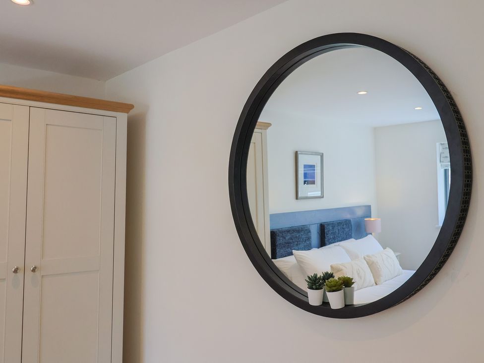 A bedroom with a mirror and wardrobe at 1 Mill Green Court in Lyme Regis