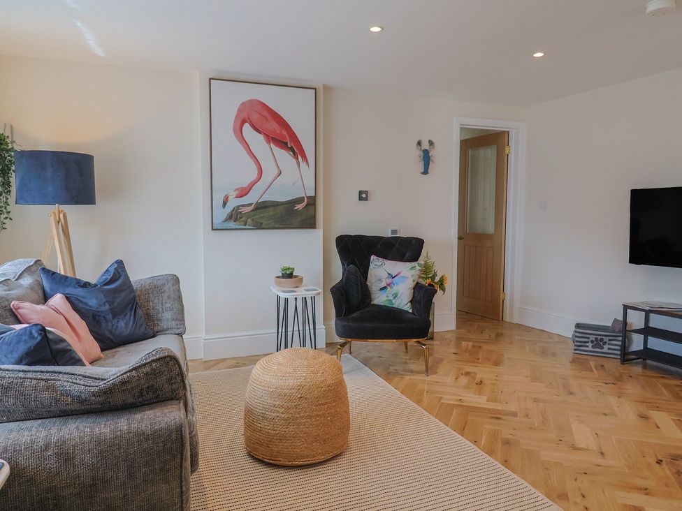 A living room with a sofa, chair, and TV at 1 Mill Green Court in Lyme Regis