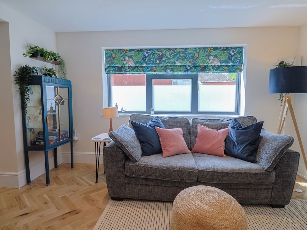 A living room with a sofa and display cabinet at 1 Mill Green Court in Lyme Regis
