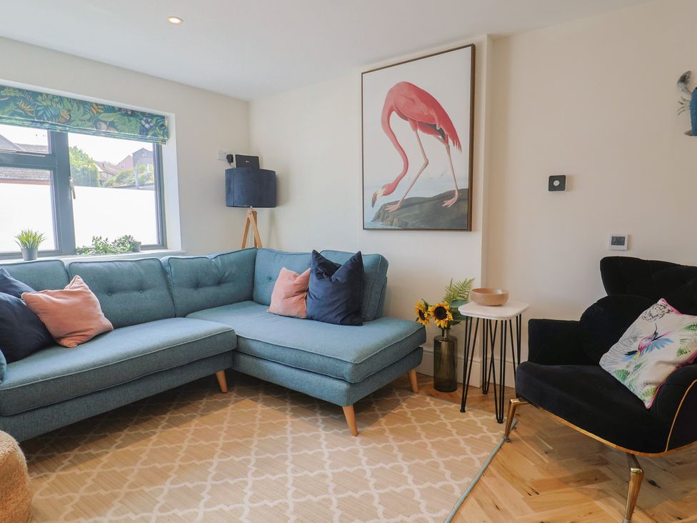 A living room with a blue sofa and a black armchair at 1 Mill Green Court in Lyme Regis