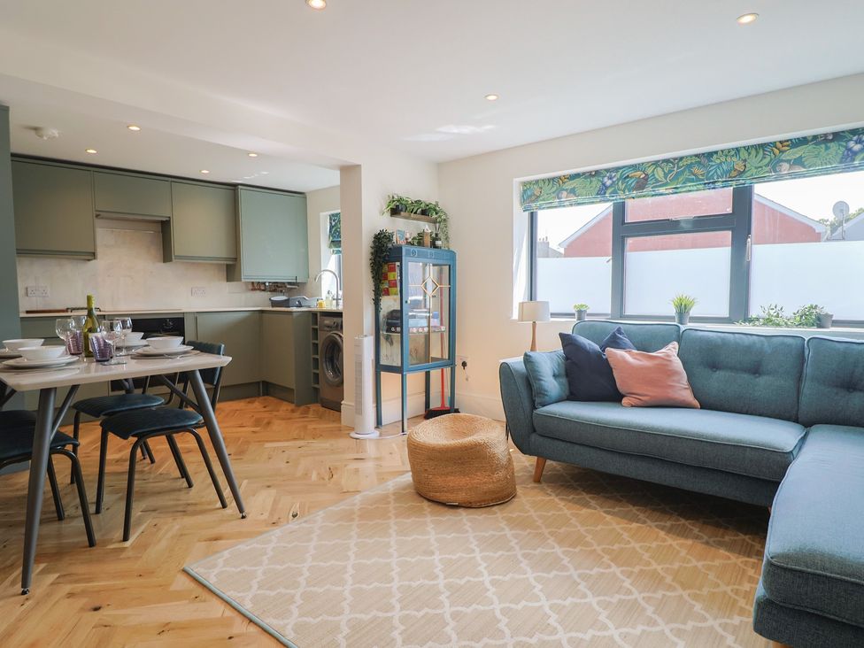 A living room with a sofa and dining table at 1 Mill Green Court in Lyme Regis