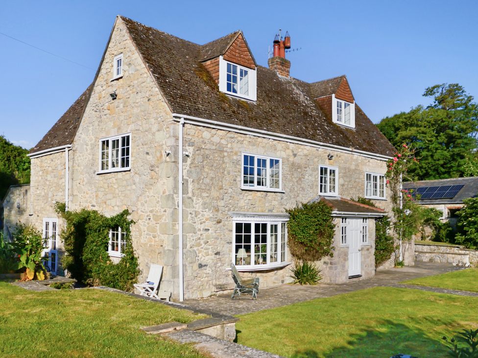 A stone house with multiple windows and a garden at Tuckers Farm in Gatcombe