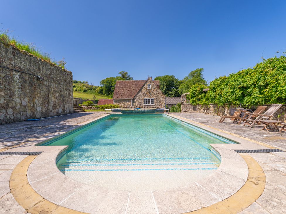 An outdoor area with a swimming pool and stone wall at Tuckers Farm in Gatcombe