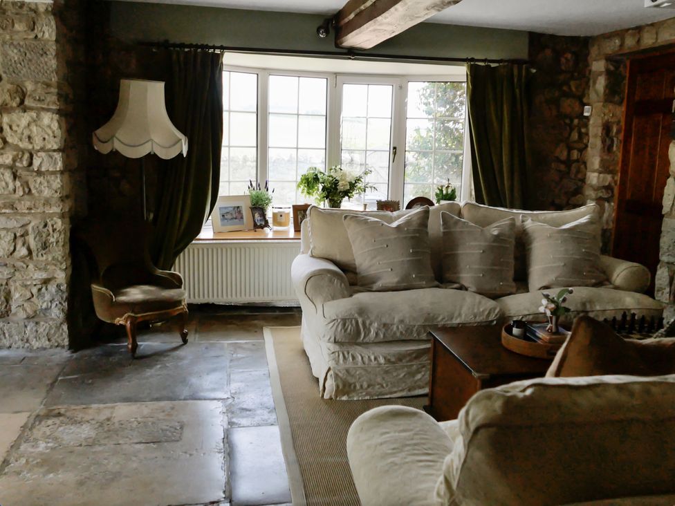 A living room with a sofa and chair next to a window at Tuckers Farm in Gatcombe