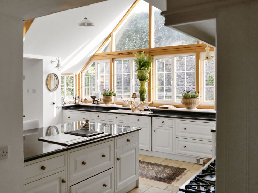 A kitchen with white cabinets and a large window at Tuckers Farm in Gatcombe