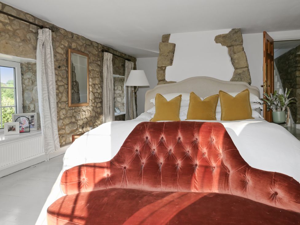 A bedroom with a bed and stone wall at Tuckers Farm in Gatcombe