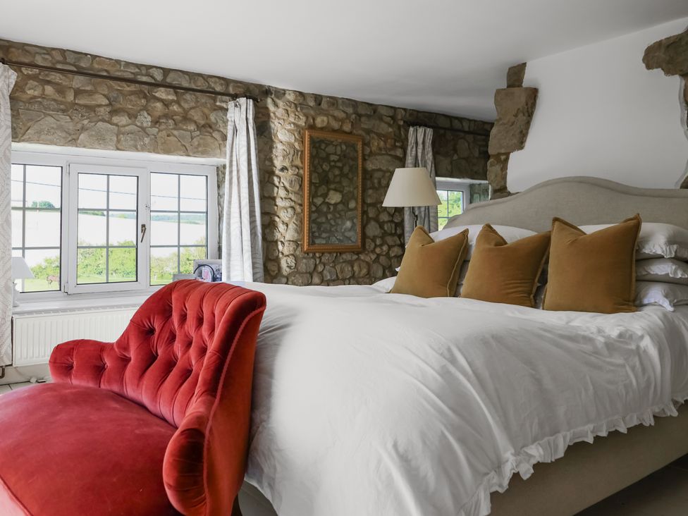 A bedroom with a bed and armchair at Tuckers Farm in Gatcombe