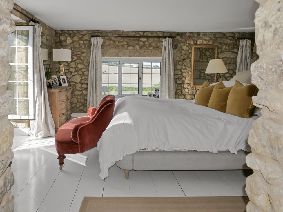 A bedroom with a bed and a chair at Tuckers Farm in Gatcombe