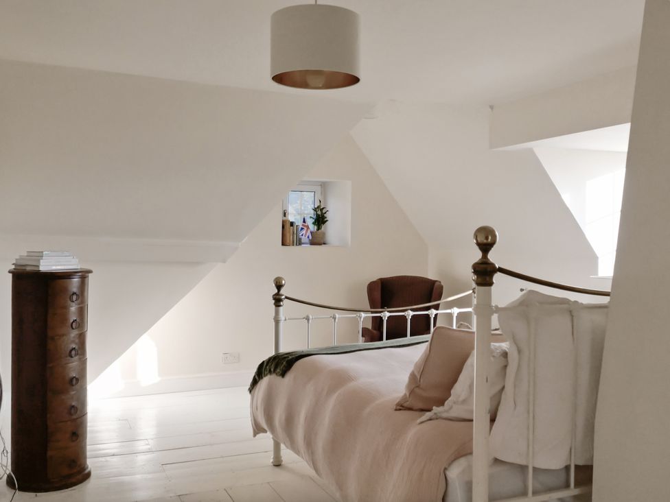 A bedroom with a bed, chair, and wardrobe at Tuckers Farm Gatcombe