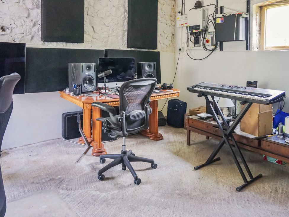 A music studio with a desk, computer, speakers, and keyboard at Tuckers Farm in Gatcombe