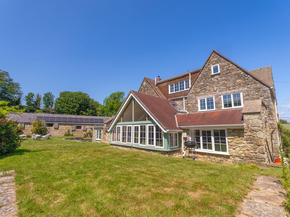 An outdoor view of a house with a patio and grass at Tuckers Farm Gatcombe