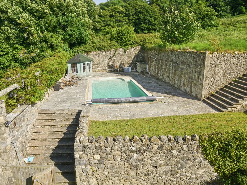 An outdoor area with a swimming pool and stone walls at Tuckers Farm in Gatcombe